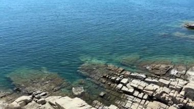 Yunanistan 'ın Kavala kentinin baş döndürücü kayalık kıyı şeridinin aydınlık bir yaz gününde havadan görünüşü. Kristal berrak mavi ve turkuaz sular su altındaki kayaları ortaya çıkarıyor..