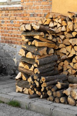 Köhne tuğla bir binanın yanında düzgün istiflenmiş odun (kırık kütükler, dallar). Sağlam bir odun yığını, klasik kış ısıtma hazırlığı..