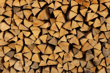 Odunların doğal dokularını ve tahıllarını gösteren düzgünce düzenlenmiş bir odun yığını. Bu bol odun yığını soğuk kış aylarında sıcaklık ve konfor sağlamaya hazırdır..