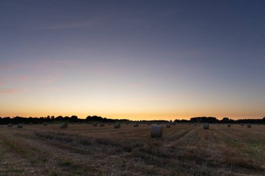 Gün batımında saman balyasıyla bir tarla