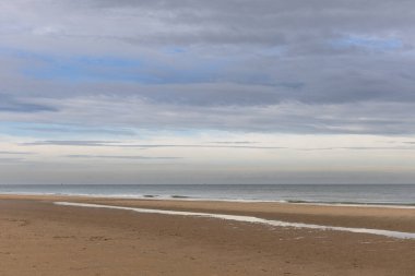 Deniz ve gökyüzü bulutlu sahil.