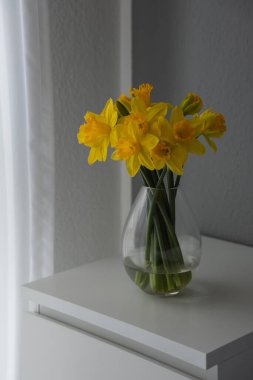 Pencere kenarındaki vazoda nergis buketi.