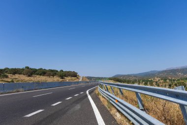 İtalya Sardunya adasında boş bir yol güzel güneşli bir günde mavi gökyüzü ve arka planda beyaz bulutlar.