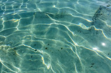 Turkuaz su yüzeyi. Suyun yüzeyinde güneş yansımaları var.