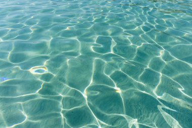 Turkuaz su yüzeyi. Suyun yüzeyinde güneş yansımaları var.