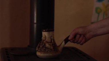Geleneksel bir şekilde kahve yapmak için eski sobanın üzerine seramik kahve koyduk. Çiftlik mutfağında kırsal bir soba. Retro mutfak aletleri. Metin - Zaporizhzhia, Ukrayna şehri