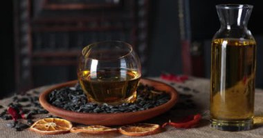 Kabuğu soyulmuş ayçekirdeği olmayan ahşap bir plaka ve altın ayçiçeği yağıyla taşralı sade bir hayat. Siyah kabuklu ayçekirdeği, çuval bezinde bir şişe bitkisel yağ ile masaya düşer.