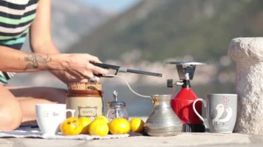 Kadın eller gaz ocağını açıyor ve Karadağ 'ın Donji Stoliv kentindeki rıhtımda piknikte açık havada kahve yapıyor. Kadın Türk Cemve 'sinde gaz ocağında öğütülmüş kahve hazırlıyor.