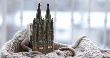 Açık havada kar yağarken yumuşak örülmüş eşarba sarılı gotik katedral şeklinde hatıra fenerlerle dolu bir kış. Mum ışığı eski kilise şeklinde bir mum tutacağının içinde yanıp sönüyor. Sıcak tutuyor.
