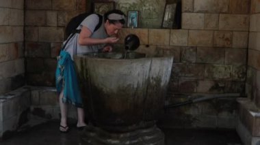 Ortodoks manastırı, kutsal Lyadovsky Rocky Manastırı, Ukrayna 'nın kutsal mekanında kadın avucunun içinden su içiyor ve kendini kutsal suyla yıkıyor.