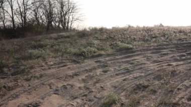 Arazinin ortasında off-road, kamera sağa dönüyor. Bozkırda kumdaki lastik izleri. Zor bir yolda yürü ve sür. Çölde yetişen kuru otlar. İzleri olan bir manzara ve hiç kimse