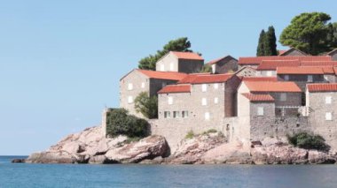 Karadağ 'ın Sveti Stefan adasının Avrupa' daki Adriyatik deniz kıyılarının manzarası. Rocky Adası ve kırmızı kiremitli çatıları olan ortaçağ taştan kale binaları. Lüks Avrupa tatil beldesi