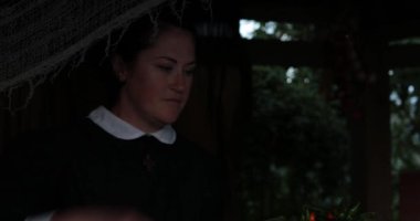 Cadılar Bayramı 'nda rahibe kostümü giymiş bir kadın kil kabuktaki baharatlı biber kabuğunu alıp büyücülük iksiriyle birlikte cam kaseye atıyor. Gotik rahibe kafatası ve mum ile sihirli iksir hazırlayın