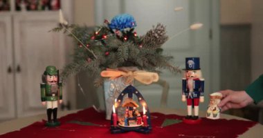 Kadınlar Noel sofrasını mum yel değirmeni ve retro fındıkkıranlarla süslerler. Kış tatili için Xmas yemeği dekorasyonu. Klasik stil geleneksel Noel süslemeleri masa örtüsü.