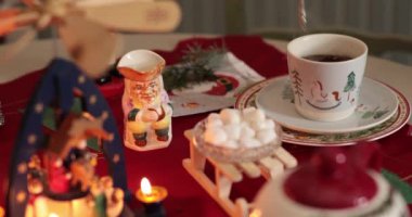 Eller şeker koyar, süt döker, kış tatili masasında sıcak çikolataya marshmallow ekler Noel süsleriyle süslenir, kutlamalar için samimi ve davetkar bir ortam yaratır..