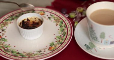 Kaşıklı el karamelize şeker hamuru kremalı brulee tatlısını kırdı. Kişi yanık krema yer. Süslü tabakta sıcak bir fincan sıcak çikolatanın yanında lezzetli bir tatlı.