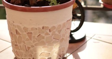 Mozaik saksı, balkon dekorasyonuna uygun eşsiz bir kalıp oluşturmak için çeşitli malzemelerle hazırlanıyor..