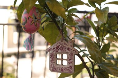 El yapımı Paskalya süslemeleri renkli bir Paskalya yumurtası ve büyüleyici ahşap bir ev süsüyle canlı bir bitki süslüyor. Bayram için mükemmel bir ortam yaratıyor..