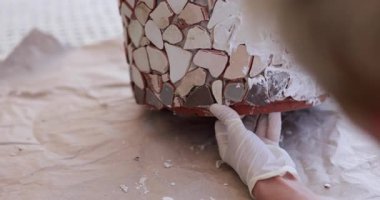 Rahat bir atölye ortamında çeşitli renkli fayanslar kullanarak mozaik bir saksı üzerinde çalışıyorum. Yaratıcı sürecin tadını çıkarırken parçaları hassasiyetle yerleştirmeye odaklanmak.