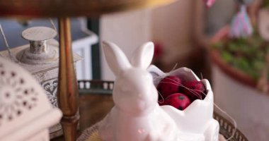 Eller dikkatlice dekoratif bir tabaktan renkli Paskalya yumurtalarını alır, yumurta boyamasının neşeli anlarını vurgular..