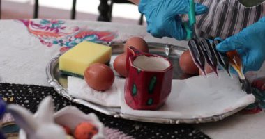 Paskalya yumurtalarının canlı renklerle süslendiği yumurta boyama sürecinin basamaklarını araştırın. Çeşitli araç ve gereçler bu mevsimsel etkinliğin yaratıcılığını gösteriyor..