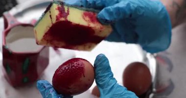 Paskalya yumurtası resmi kırmızı boyaları ve sünger kullanarak yaratıcı teknikleri içeren detaylı bir süreçten geçiyor.