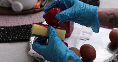 Renkli Paskalya yumurtaları yumurta boyama sürecinde sünger ve kırmızı boya kullanılarak yaratılır, neşeli bir bayram geleneği için çeşitli teknikler ve canlı renkler sergilenir..