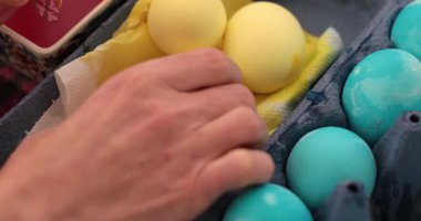 Paskalya yumurtalarını parlak mavi boyalarla süslüyor. Yumurta boyama sürecinin bu aşaması festival sembolleri ve desenleri tasarlamak için yaratıcı teknikler sergiliyor..