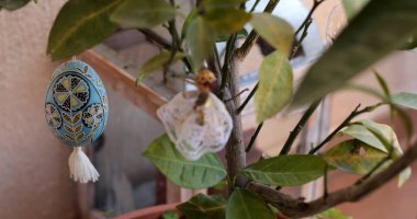 Çarpıcı bir Paskalya yumurtası piranası yeşil bir bitki üzerinde zarif bir şekilde sergilenir. Etrafı canlı Paskalya süsleriyle çevrilidir. Bu da ayar ortamının neşeli atmosferini güçlendirir..