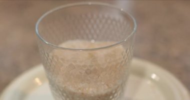 Mutfak terazilerindeki şeffaf cam bardakta kahverengi kamış şekeri ölçüyorum. Pişirme ve pişirme için gerekli malzemeleri tartıyorum. Cama odaklan, kamera aşağı in. Yemek pişirme aşaması.