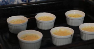 Pişirme tepsisindeki küçük üzümlü kremalı tatlıyı hazırlıyorum. Küçük fırın kalıplarında creme brulee. Odaklanma arka plandan ön plana hareket eder. Aşama aşama altın kabuklu ikramlar için pişirme