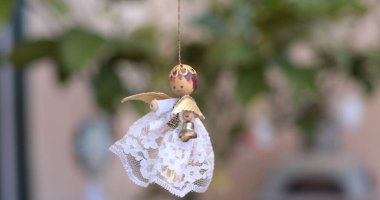 Çekici melek süslemeleri, dantelli ve küçük detaylarla süslenmiş, mevsimsel kutlamalar için uygun bir şenlik ruhunu somutlaştıran, ya da sıcak Noel ev havası veren sakin bir ortamda nazikçe sallanıyor..