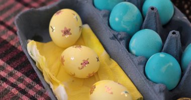 Canlı bir ortamda, sarı mavi tonda Paskalya yumurtaları süsleniyor. Etkinlik, yumurtalara karmaşık tasarımlar uygulanarak renklendirme sevincini vurgulayan Pysanky sanatını sergiliyor..