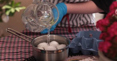 Eldivenli bir insan Paskalya yumurtalarını boyamak için yumurta dolu bir kaba su döker. Bu şenlikli etkinlik canlı bir ortamda gerçekleşiyor..