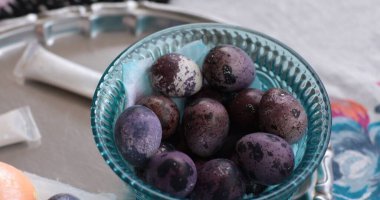 Mor Paskalya yumurtaları ve bıldırcın yumurtaları açık bir dekoratif kasede sergilenir..