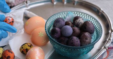 Canlı bir Paskalya yumurtası ve bıldırcın yumurtası gösterimi. İnci boyası detaylarıyla. Dekor, neşeli bir atmosferi tatil kutlamaları için mükemmel bir yere davet ediyor..