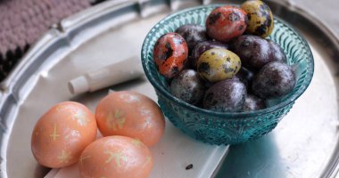 Süslü inci süslemeli Paskalya yumurtaları ve doğal bıldırcın yumurtaları şık bir kasede sergilenir. Bu canlı dekorasyonlar ilkbaharın gelişini ve Paskalya kutlamalarının neşesini kutluyor..