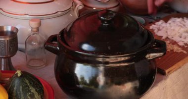 Balkabağı çorbası pişirme sahnenin ortasına konacak. Taze malzemeler siyah tencerede birleşecek. Eller kapağı açın ve çorbaya malzeme ekleyin. Baharatlar ve sebzeler, Şükran Günü toplantıları için yemek yapmak.