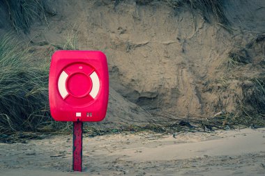 Life ring box sits on the beach, the sun low in the sky casting a golden light over Cruden Bay Beach, Aberdeenshire, Scotland on a cold New Year's Day. clipart