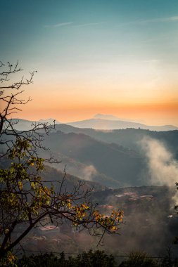 Yuvarlanan tepeler, yemyeşil ormanlar ve İtalya 'nın Amalfi Sahili' nde altın bir gökyüzü içeren günbatımı manzarası. Huzurlu ve büyüleyici bir doğal manzara. Resmedilmeye değer kırsal çevrede sis yükseliyor..