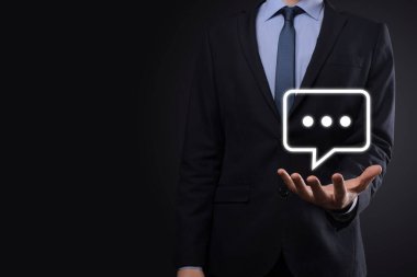 Elinde mesaj ikonu tutan bir iş adamı, elinde baloncuklu konuşma tebligat işareti var. Sohbet simgesi, SMS simgesi, yorum simgesi, konuşma baloncukları.