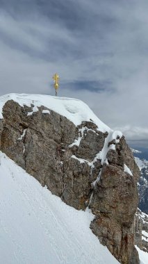 Zugspitze Zirvesi 'nde Altın Haç, Almanya. Çarpıcı bir altın haç, Almanya 'nın en yüksek zirvesi olan Zugspitze' nin deniz seviyesinden 2,962 metre yükseklikte duruşu oldu. Kayalık bir arkaplana karşı ayarlandı