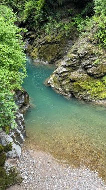 İtalya, Bellano 'daki Gorge Gölü yakınlarında turkuaz su. İtalya 'nın Bellano kentinde Como Gölü yakınlarındaki dar bir vadiden geçen sakin bir turkuaz nehri, yosun kaplı kayalar ve canlı yeşil kayalarla çevrilidir.