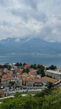 Lake Como and Mountain View with Charming Village Bellano in Italy. Scenic view of Lake Como surrounded by lush mountains, with a picturesque village of red-roofed houses in the foreground. A peaceful clipart