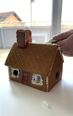 Gösterişli zencefilli kurabiye evi. Parlak Ayar 'da renkli kremayla. Dondurmayla süslenmiş, yaratıcı şenlik ayrıntıları sergilenen zencefilli bir evin yakın çekimi. Sahne aktarır