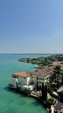 Picturesque Turkuaz Gölü Garda ve Sirmione, İtalya 'da Rıhtım Kıyısı Mimarisi. Sirmione 'nin deniz manzarası yükseldi. Garda Gölü' nün büyüleyici turkuaz sularını ve yemyeşil sularını aydınlattı.