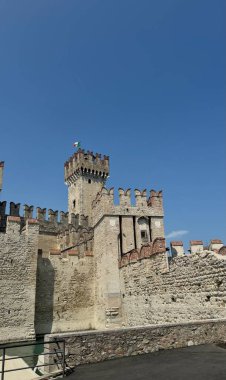 Sirmione, İtalya 'da Saliger Kalesi. Bu çarpıcı görüntü İtalya 'nın Sirmione kentindeki Scaliger Kalesi' ni güçlü ortaçağ duvarları ve kulede dalgalanan bir İtalyan bayrağıyla yakalıyor. Temiz.