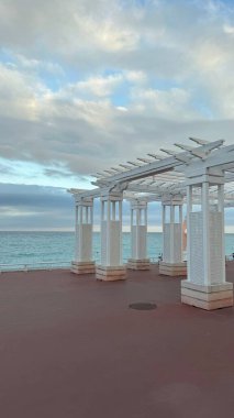 Seafront Arches on the Promenade, French coast, Mediterranean Sea. White decorative arches along the Promenade des Anglais in Nice, France, with the Mediterranean Sea in the background. A serene clipart