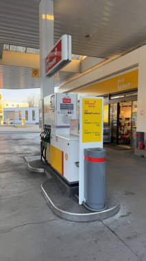 22.03.2025 Almanya: Yakıt Pompalı Modern Shell Benzin İstasyonu ve Market Dış Görünümü. Yakıt pompaları, marka tabelaları ve ilave bir bakkal bulunan Urban Schell benzin istasyonu