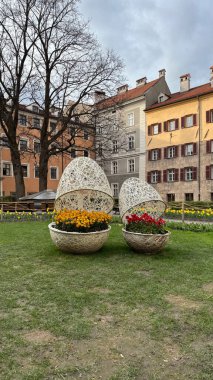 Innsbruck 'taki Wicker Shapes' da Dekoratif Çiçeklerle Güzel Şehir Gösterimi. Dekoratif hasır yapılar içinde çağdaş çiçek düzenlemelerinin yer aldığı şehir parkı sahnesi
